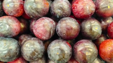 Bir süpermarkette yığılmış taze kırmızı eriklerin yakın çekimi.