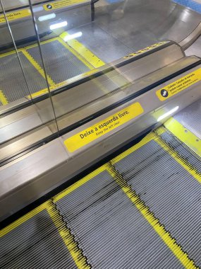 A close-up view of an airport or shopping mall moving walkway with a security sign. clipart