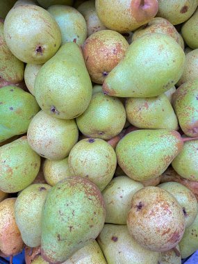 Canlı yeşil armutlar bir araya toplanmış, doğal benekli derilerini gösteriyorlar..