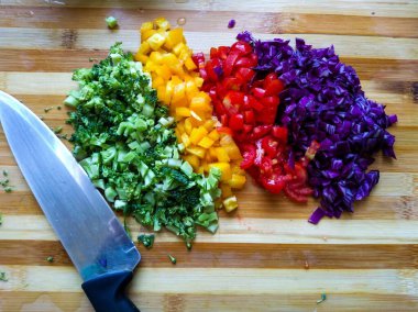 Renkli sebzeler, küp şeklinde kesilmiş ve uyum içinde renklerle ayrılmış. Sebzeler kesme tahtasının üzerinde yan yana konur..