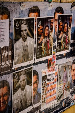 Katmanlı posterlerle kaplı, şehir kültürü ve sokak sanatıyla ilgili hikayeler anlatan dokulu bir duvar..