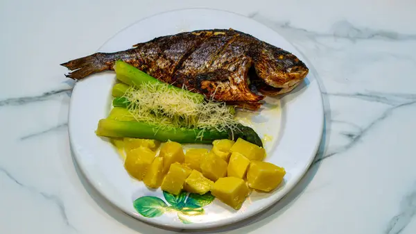 fırında Dorado balığı, taze yeşil kuşkonmaz rendelenmiş peynir serpiştirilmiş ve patates doğranmış..