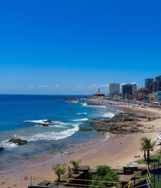 Güneşli bir günde, Barra Deniz Feneri 'nin detaylarının arka planda göründüğü güzel bir tropikal manzarayı gösteren güzel bir sahil görüntüsü.