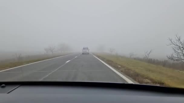 途中で不気味な裸の木と霧の道に移動車のフロントガラスの外を表示します 静かな霧の天気 風光明媚な晩秋の季節 — ストック動画