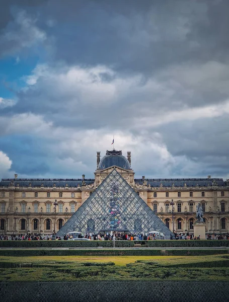 フランスのパリにあるルーブル美術館の外の景色 近代的なガラスピラミッドを中心にした歴史的な宮殿の建物 垂直方向の背景 — ストック写真
