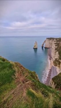 Sightseeing view famous rock known as the Aiguille of Etretat in Normandy, France. Famous cliffs Falaise d'Aval washed by La Manche channel waters. Beautiful coastline vertical scenery
