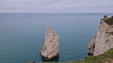 Etretat 'ın Aiguille' ü olarak bilinen ünlü kayanın doğal görüntüsü. Falaise d 'Aval kıyı şeridi kayalıkları ve ufuktaki mavi okyanus suyu.