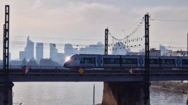 Metro trains moving on a railway bridge in Paris, France with La Defense metropolitan district on the background