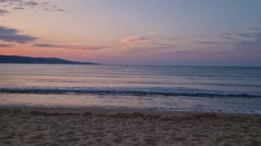 Kumda köpüklü dalgalar ve ufukta renkli gökyüzü ile denizde şafak. Bulgaristan 'ın Sunny Beach kıyı şeridi. Yaz ve seyahat geçmişi