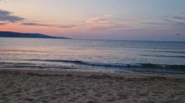 Kumda köpüklü dalgalar ve ufukta renkli gökyüzü ile denizde gün doğumu. Bulgaristan 'da yaz ve seyahat geçmişi, Sunny Beach kıyı şeridi