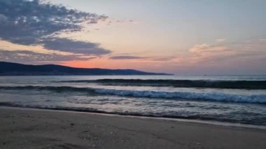 Kumda köpüklü dalgalar ve ufukta renkli gökyüzü ile denizde şafak. Bulgaristan 'ın Sunny Beach kıyı şeridi. Yaz ve seyahat geçmişi