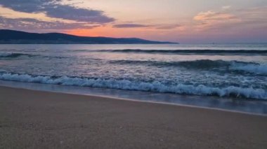Sabahın erken saatlerinde sahilde, deniz üzerinde güneşin doğuşunu huzurlu bir şekilde seyrederken. Sakin deniz manzarası, doğal arka plan. Yaz tatili ve seyahat konsepti
