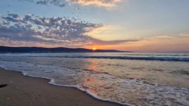 Sabahın erken saatlerinde sahilde, denizin üzerinde güneşin doğuşunu gören güzel bir manzara ve çerçeveye doğru koşan bir adam.