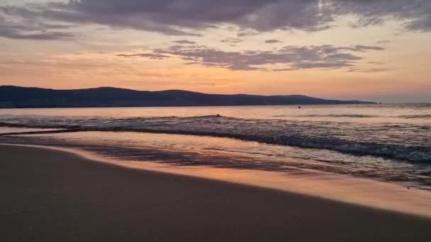 日出在海面上 泡沫般的波浪在沙滩上 五彩斑斓的天空在地平线上 保加利亚桑尼海滩海岸线夏季和旅行背景 — 图库视频影像