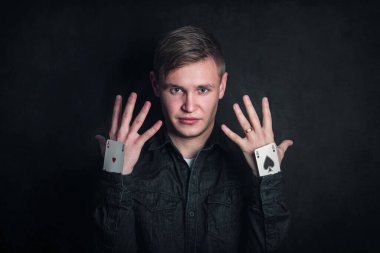 Kendine güveni tam bir kumarbaz, kolları aslarla dolu. İllüzyonist, karanlık arka planda izole edilmiş oyun kartlarıyla numaralar gösteriyor. Kumar oyunları, şans ve yanılsama konsepti