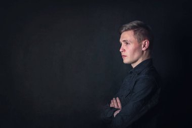 Derin düşüncelere dalmış genç adam portresi, karanlık bir duvar arkasında dalgın görünüyor. Erkek öğrenci soruları olduğu gibi yansıtır