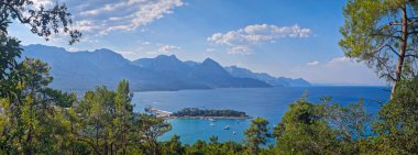 Panoramik Kemer kıyı manzarası. Arkasında görkemli Taurus dağları olan canlı deniz manzarası. Ay Işığı Sahili 'ne ve hareketli bir limanı olan yarımadaya en üst manzara. Türkiye 'de yaz tatili