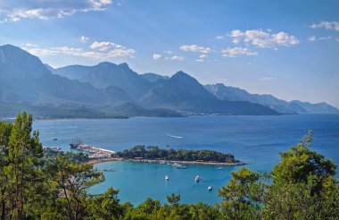 Panoramik Kemer kıyı manzarası. Arkasında görkemli Taurus dağları olan canlı deniz manzarası. Ay Işığı Sahili 'ne ve hareketli bir limanı olan yarımadaya en üst manzara. Türkiye 'de yaz tatili