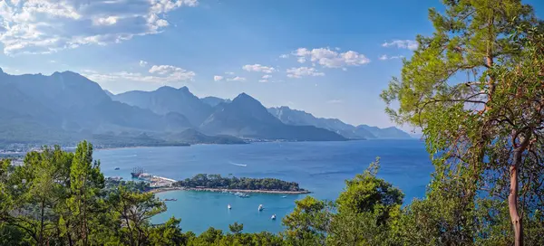 Panoramik Kemer kıyı manzarası. Arkasında görkemli Taurus dağları olan canlı deniz manzarası. Ay Işığı Sahili 'ne ve hareketli bir limanı olan yarımadaya en üst manzara. Türkiye 'de yaz tatili