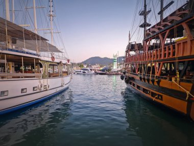 Alacakaranlıkta Kemer marinası, birden fazla rıhtımlı tekne ile dolu. Limanın ışıkları ve sahil şeridi sakin deniz suyunu yansıtıyor.
