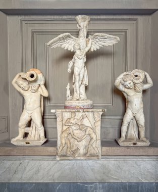 VATİKAN ŞEHRİ, Roma, İtalya - 02 Ağustos 2025 Pio-Clementino Müzesi içinde mermer heykel grubu ortasında kanatlı Ganymede ve omuzlarında büyük bir kavanoz tutan iki küçük erkek figürü