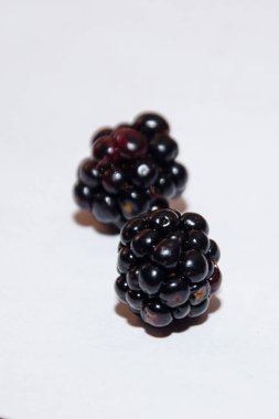 Beyaz arka plana dağılmış siyah sulu böğürtlenler. böğürtlen