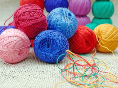 Gri çuval bezi üzerindeki çok renkli topların iplikçikleri. çok renkli iplikçikler ve açılmamış iplikler