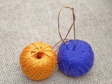 Skeine saplanmış mavi ve sarı iplikli bir iğne.