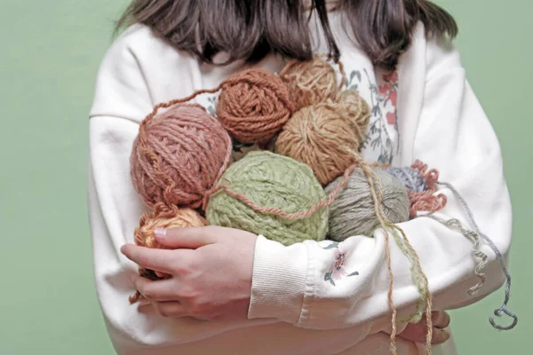 the girl holds skeins of colorful yarn in her hands. Hobi knitting yarn, handmade.