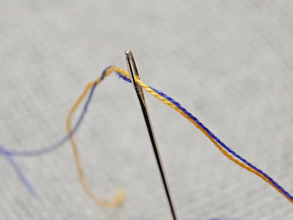 stock image needle with blue and yellow threads, close-up