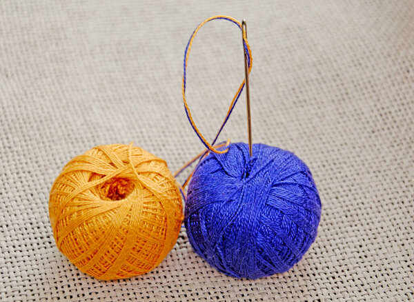a needle with a blue and yellow thread stuck in a skein