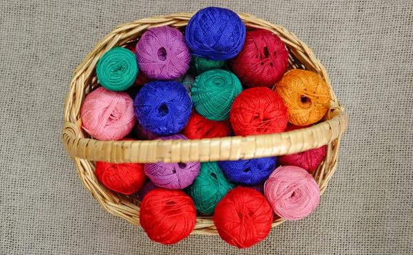 multi-colored skeins of thread in a wicker basket, top view. needlework threads, close-up