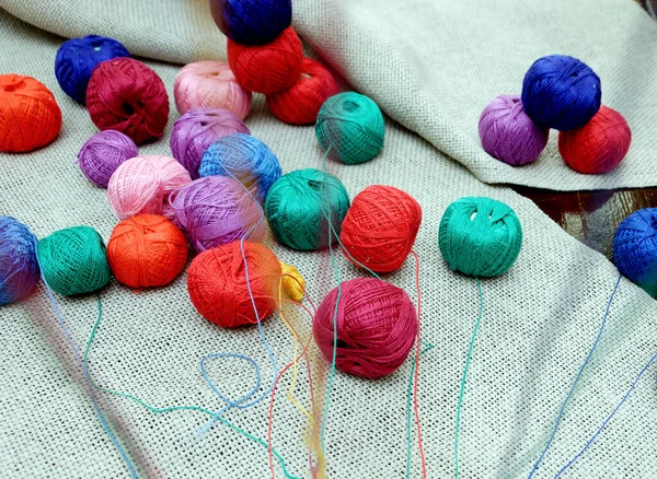 unwound threads from multi-colored balls on gray burlap. multi-colored balls of threads with unwound threads