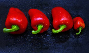 Kırmızı biber. Koyu arkaplanda çiğ taneleri, sebzeler, tatlı biberler olan olgun kırmızı biberler.