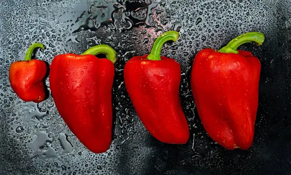 Kırmızı biber. Koyu arkaplanda çiğ taneleri, sebzeler, tatlı biberler olan olgun kırmızı biberler.