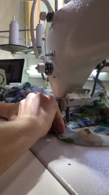 Endüstriyel dikiş makinesine güzel hafif kumaşlar dikiyor. Stüdyoda kıyafet tamiri ve terziliği. Tanımlanamayan bir kadının eli kumaşa yerleştirilmiş iğneyi çıkarır ve dikmeye başlar..