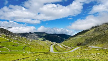 Peru 'daki Regin Ncash' deki Sierra Dağları 'nda güzel bir manzara yolu. Arkasında dağlar ve tepeler olan yemyeşil bir vadi boyunca kıvrımlarla dolu bir yol.. 