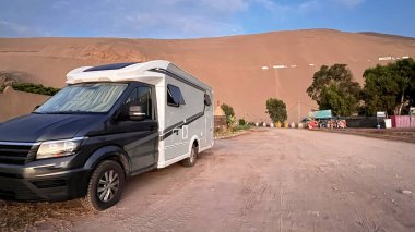 Sahilde Peru 'da dururken modern bir karavan. Pan American Otoyolu çöl ve kum tepelerinden geçiyor. Tekerlekli karavan
