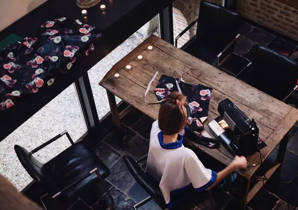 Kadın tasarımcının siyah ev dikme makinesini tahta masaya diktiği en iyi manzara. Hobi dikiş, terzilik, tasarım, el işi kavramı.