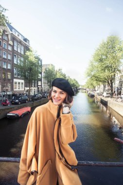 Amsterdam sokaklarında poz veren güzel, zarif bir kadın kanal önünde Avrupa 'da yaz tatilinin tadını çıkaran mutlu bir kadın turist. 