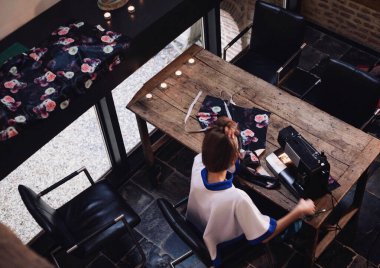 Tanımlanamayan kadın tasarımcının siyah ev dikme makinesini tahta masaya dikmesi. Hobi olarak dikiş, terzilik, tasarım, el işi.