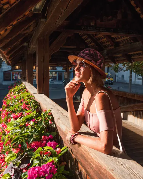İsviçre, Luzern 'deki Chapel Köprüsü' nde duran güzel bir kadının portresi. Manken şapka takıyor, güneş gözlüğü takıyor, omuzları açık, seyahatinin tadını çıkarıyor.. 
