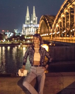 Güzel, zarif bir kadın, Almanya 'daki Köln' ün ufuk çizgisi manzarasının önünde oturuyor. 