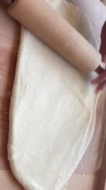 Tahta tokalı hamuru yuvarlayan bir adamın el kamerası görüntüsü. Ev yapımı pişirme, adım adım aşçılık dersi, hazırlık, pasta