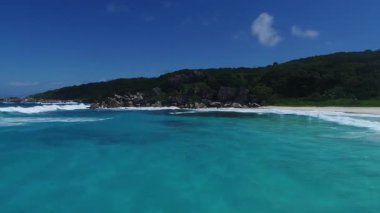Seyşeller Adası La Dique 'deki sahil şeridinin video görüntüleri. Turkuaz deniz suyu ve yeşil manzarayla sona eren eşsiz kaya oluşumları üzerinde insansız hava aracı görüntüsü, mükemmel cennet yolculuğu varış noktası..