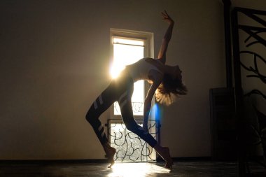 Sıska sporcu kadın arka planda bando dansçısı pozu veriyor. Altın güneş ışığı nereden geliyor? Sabah yogası, dans, kişisel bakım, aktif yaşam tarzı, esneme.