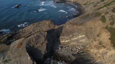 Portekiz 'in Alentejo bölgesindeki görkemli kayalarla vahşi Atlantik' in peyzaj görüntülerinin maliyeti. İnsansız hava aracı, etkileyici kaya oluşumları ve mavi dalgalı deniz manzaralı kıyı şeridini yükseltti..