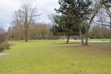 Ziyaretçiler, uzun ağaçlar ve sakin bir atmosferle çevrili yeşil bir parkta huzurlu bir gezinti yaparak günlük yaşamın karmaşasından mükemmel bir kaçış yaratıyorlar..