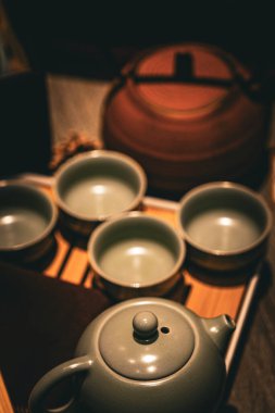 Seramik çaydanlık ve bambu tepsisinde düzgün bir şekilde dizilmiş eşleşen fincanlar seramik bir çay setine sahiptir. Yumuşak ışık sıcak bir ortam yaratır, rahatlatır..