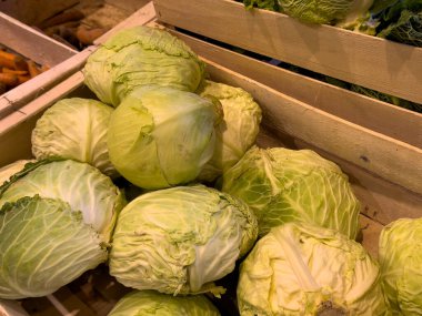 Taze yeşil lahanalar ahşap sandıklara yerleştirilip canlı renkleri ve canlı dokuları sergileniyor. Bu yerel pazar mevsimlik ürünler sunuyor ve çok sayıda ziyaretçi çekiyor..